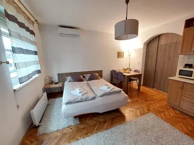 a bedroom with a bed and a table and a kitchen at MB Deluxe Apartment in Visoko