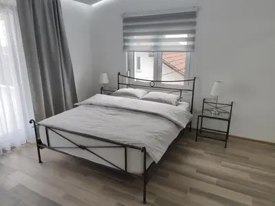 a bedroom with a black bed and a window at Evita Apartmani Šibovska in Prnjavor
