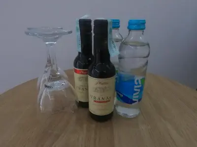 three bottles of wine and a glass on a table at Evita Apartmani Šibovska in Prnjavor