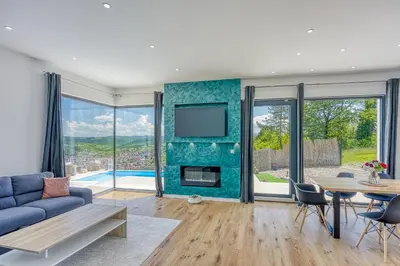 a living room with a couch and a tv and a table at Villa Hill with Private Pool in Bosanska Krupa