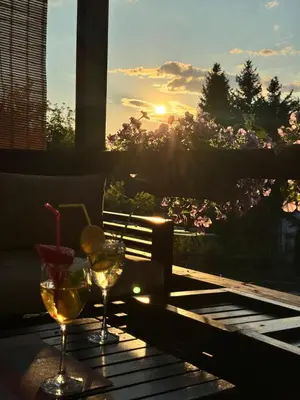 two glasses of wine sitting on a table with the sunset at Perla Accommodation in Visoko