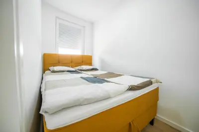 a bed with a wooden headboard in a bedroom at Liberty Apartments in Tuzla