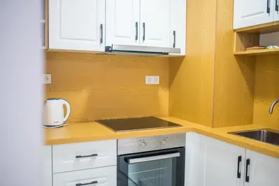 a kitchen with white cabinets and a stove top oven at Liberty Apartments in Tuzla