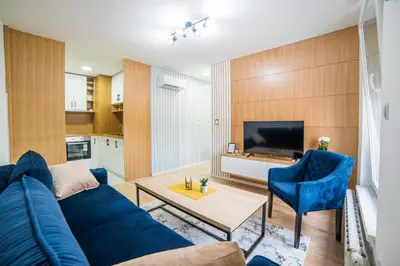 a living room with a blue couch and a tv at Liberty Apartments in Tuzla