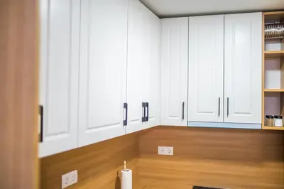 a kitchen with white cabinets and a wooden floor at Liberty Apartments in Tuzla