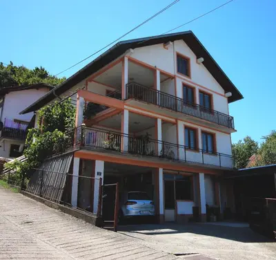 a large white building with a balcony and a car at Apartman Komfor in Banja Luka
