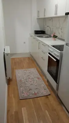 a kitchen with white appliances and a rug on the floor at Mercy Deluxapartment in Visoko