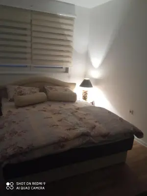a bedroom with a bed with a lamp and a window at Mercy Deluxapartment in Visoko