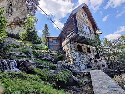 a house on a rocky hill with a waterfall at Prokosko Resort in Fojnica