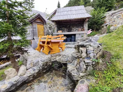 a log cabin with a table and chairs next to a stream at Prokosko Resort in Fojnica
