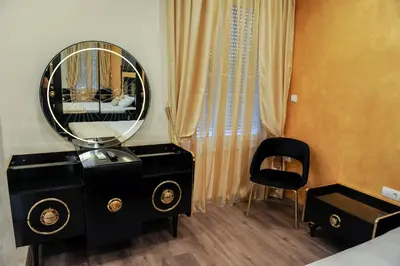 a vanity with a mirror and a chair in a room at Apartmani President I in Banja Luka