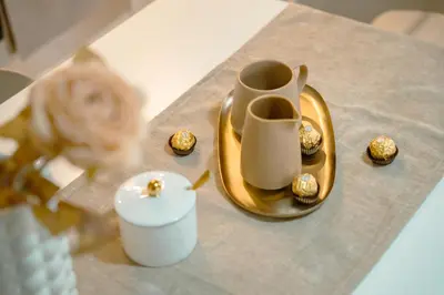 a table with a gold plate with a vase and a candle at Paradise in Bihać
