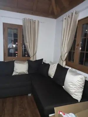 a black couch in a living room with windows at Natural Paradise in Bosanska Krupa