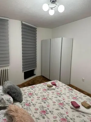 a bedroom with a bed with a floral bedspread at Apartman Tamara in Doboj