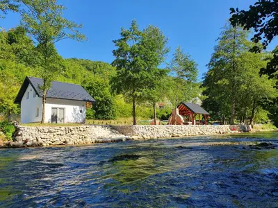 a house next to a river with a stone wall at Otoka Josikovic in Šipovo