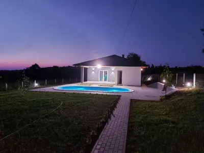 a small house with a swimming pool at night at Vikendica Fenix in Banja Luka