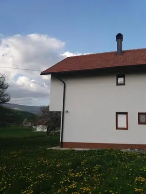 a white building with a red roof and a field of flowers at Villa Goleš Travnik in Travnik