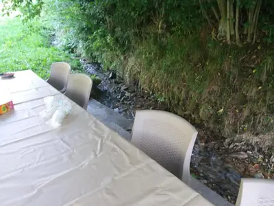 a table and chairs with a white table and a river at Villa Goleš Travnik in Travnik