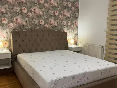a bed in a bedroom with flowers on the wall at Apartman Ana in Doboj