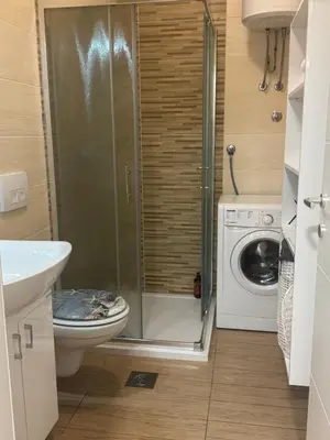 a bathroom with a toilet and a washing machine at Apartman Ana in Doboj