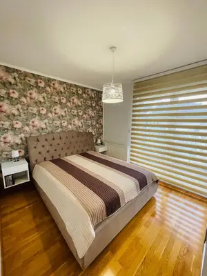 a bedroom with a large bed with a floral wall at Apartman Ana in Doboj