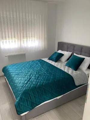 a bed with a green comforter in a bedroom at Slijepcevic in Teslić
