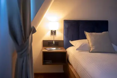 a bed with a blue headboard and a table with a lamp at Resort Una Park in Bihać