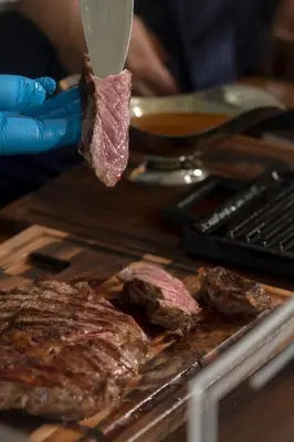 a person cutting a piece of meat with a knife at Resort Una Park in Bihać