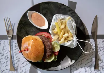 a plate of food with a hamburger and french fries at Resort Una Park in Bihać