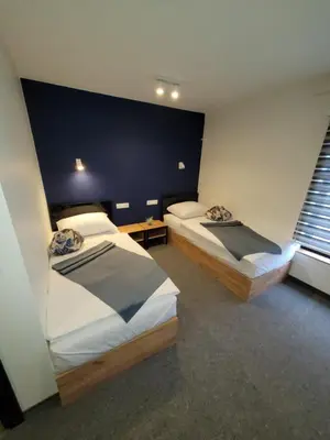 two beds in a room with two windows at Motel Bihać in Bihać