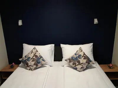 a white bed with two pillows and a blue wall at Motel Bihać in Bihać