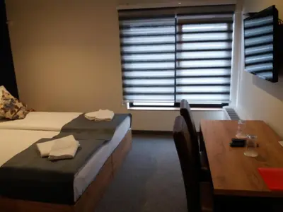 a room with two beds and a table and a window at Motel Bihać in Bihać