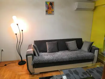 a black couch in a living room with a lamp at Milgor in Banja Luka