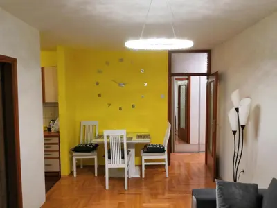 a dining room with a yellow wall with a clock at Milgor in Banja Luka