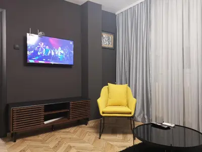 a living room with a yellow chair and a tv at City-centar in Banja Luka