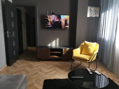 a living room with a tv and a yellow chair at City-centar in Banja Luka