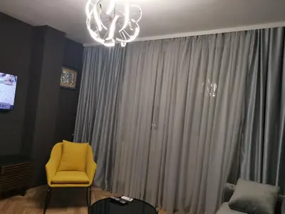 a yellow chair in front of a window with a chandelier at City-centar in Banja Luka