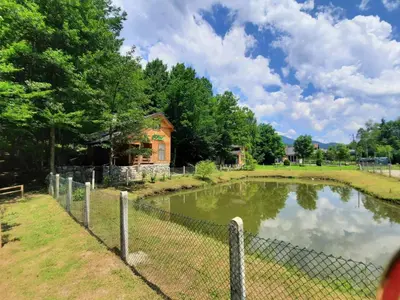a fence around a pond in front of a house at Vikendice Bungalovi Menzil in Zavidovići