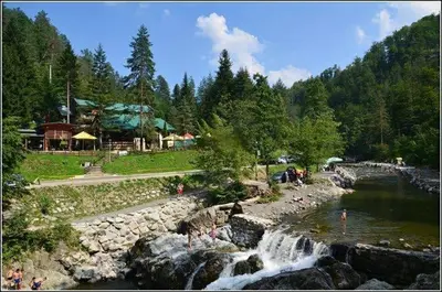 a group of people standing by a river with a waterfall at Vikendice Bungalovi Menzil in Zavidovići