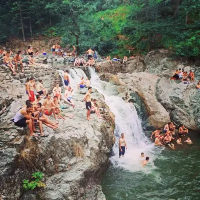 a group of people swimming in a waterfall at Vikendice Bungalovi Menzil in Zavidovići