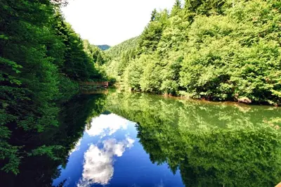 a river with a reflection of the sky in the water at Vikendice Bungalovi Menzil in Zavidovići