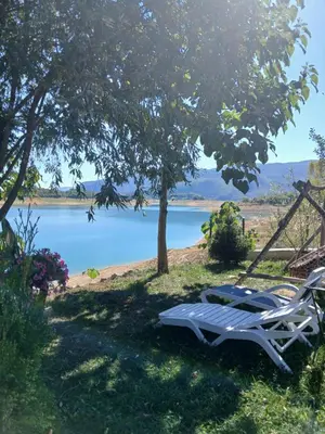 a table and chairs under a tree next to a lake at ''Lake House Jana'' Ramsko Jezero in Prozor