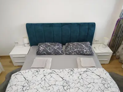 a bed with a blue headboard and two pillows at Apartment M & N in Banja Luka