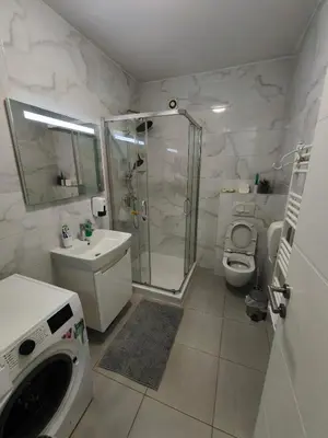 a bathroom with a shower and a sink and a washing machine at Apartment M & N in Banja Luka