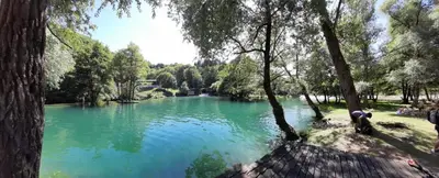 a green lake with people standing in front of it at Paulinio in Jajce