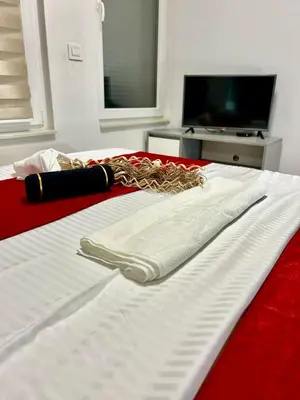 a white and red bed with a towel on it at Apartman Nova Varos Banjaluka in Banja Luka