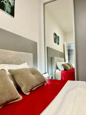 a bedroom with a red bed with a mirror at Apartman Nova Varos Banjaluka in Banja Luka