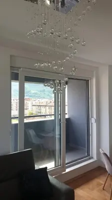 a living room with a chandelier in front of a window at Apartman Venecija in Banja Luka