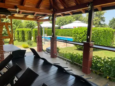 a patio with chairs and a table and a pool at Family resort TRAPISTI in Banja Luka