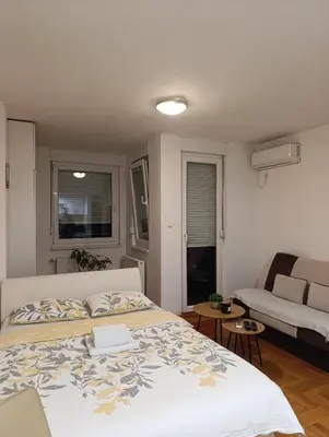 a bedroom with a bed and a living room at Apartman Garden in Banja Luka
